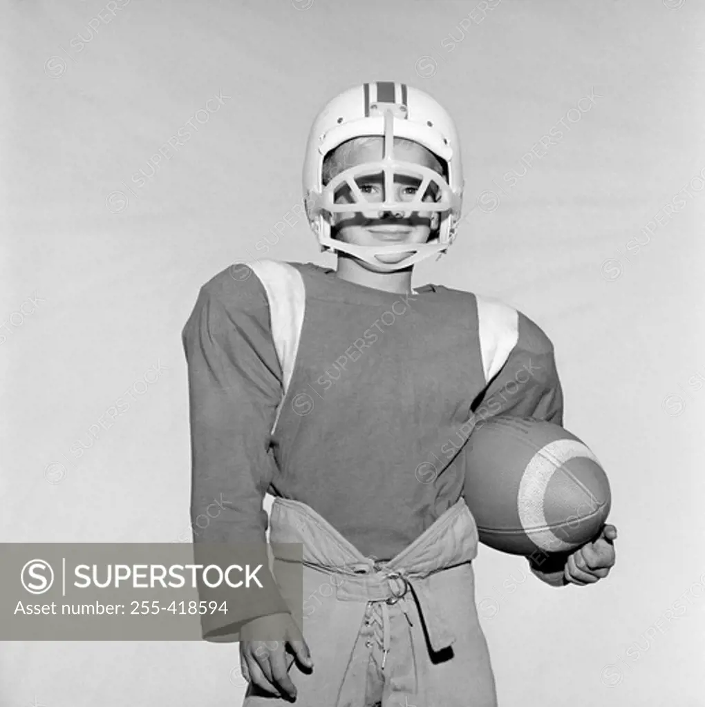 Boy wearing football helmet and holding football