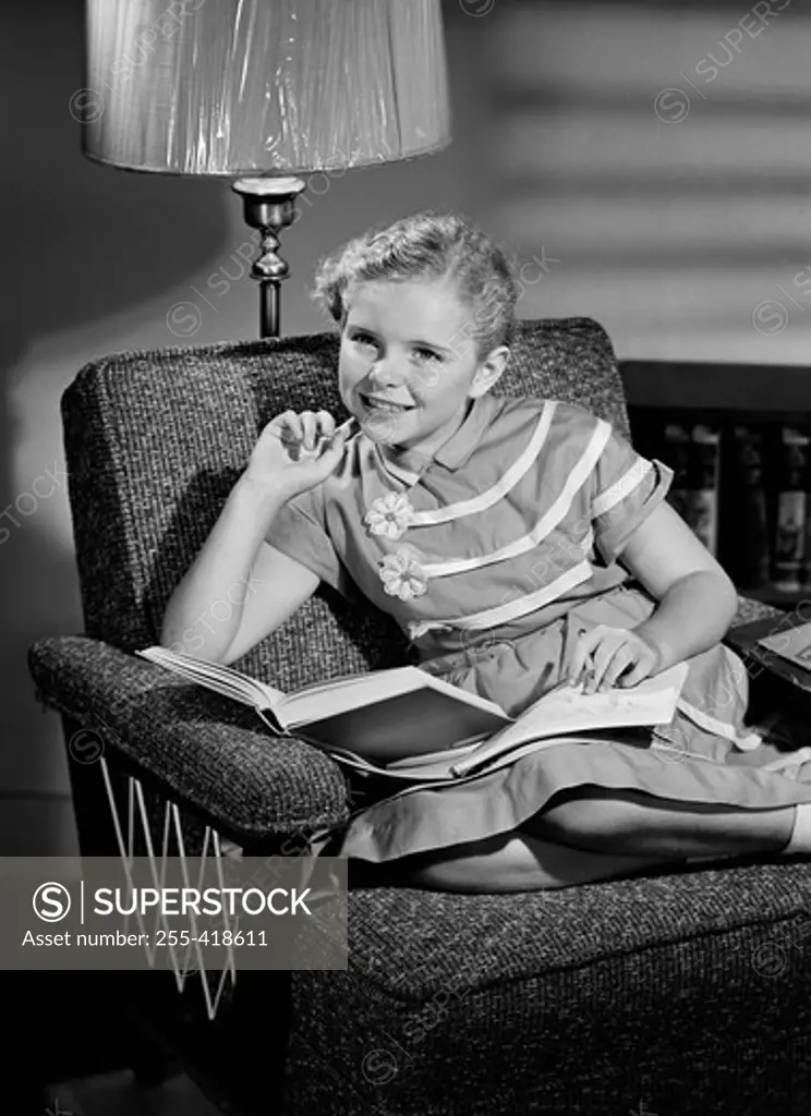 Girl sitting on armchair and reading book
