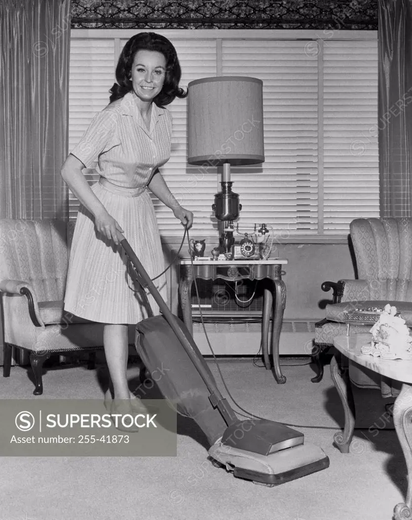 Portrait of a young woman using a vacuum cleaner