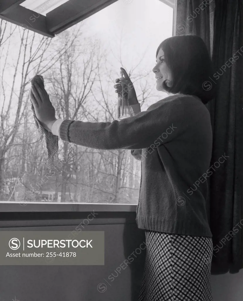 Side profile of a young woman cleaning a window
