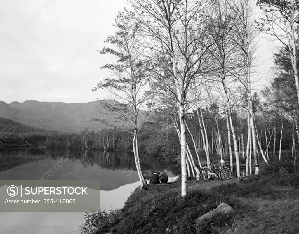 USA, New Hampshire, Shelburne, Cyclists resting on banks of Androscoggin River