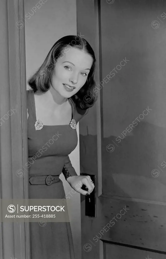 Beautiful young woman emerging from door