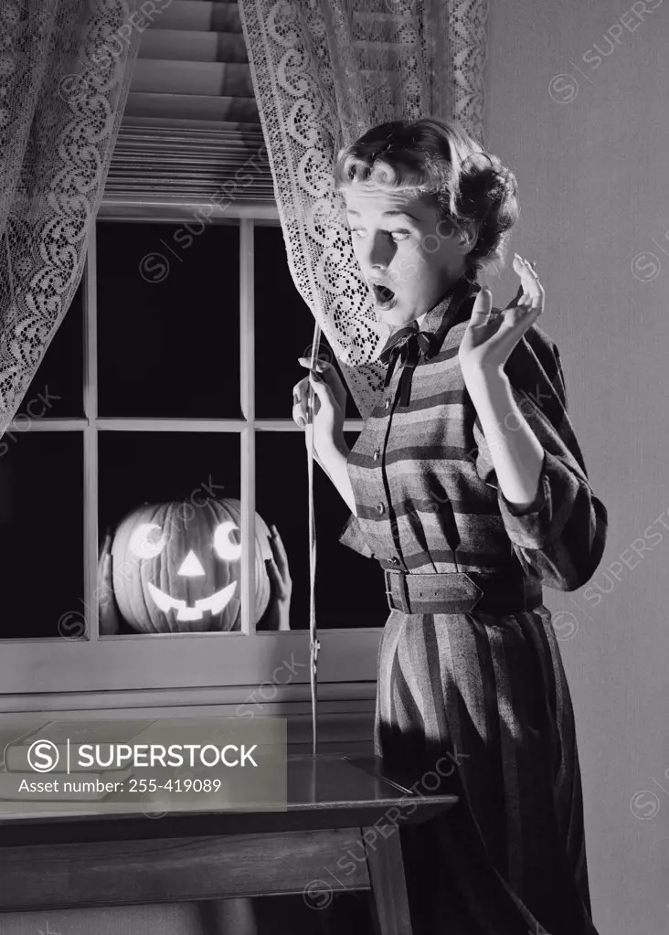 Woman shocked by jack o lantern in window