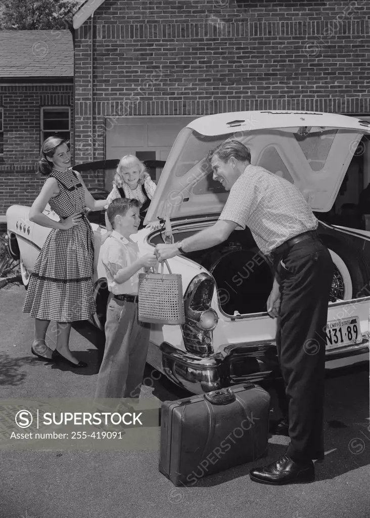 Parents with children loading suitcases into car