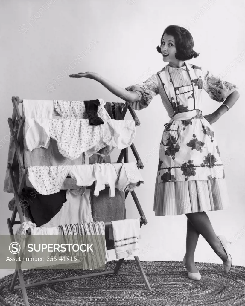 Portrait of a young woman standing near a drying rack