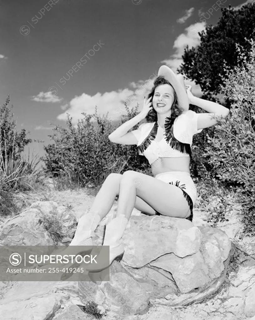 Cowgirl sitting on rock