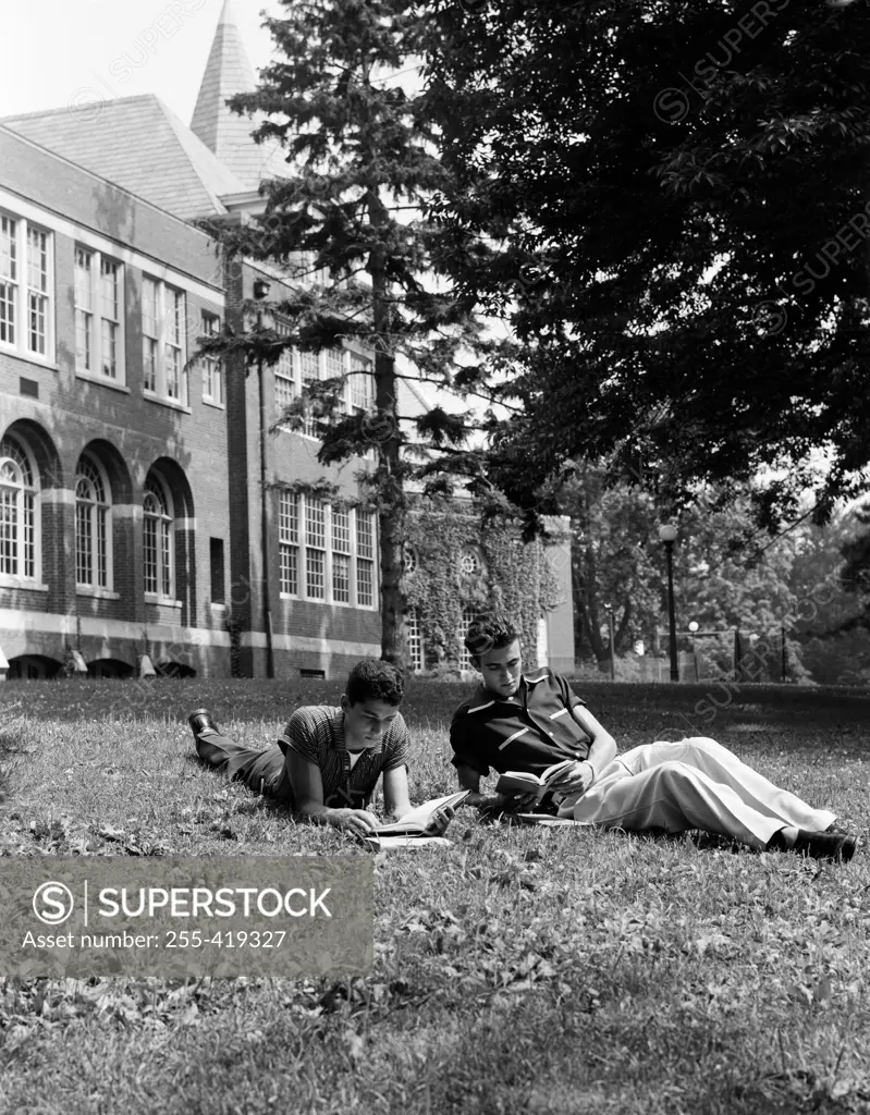 Two student lying on lawn and learning