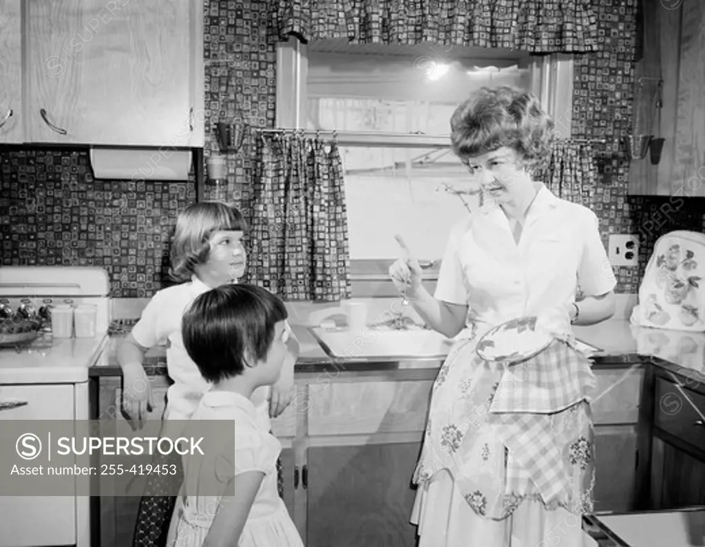 Mother reprimanding children in kitchen
