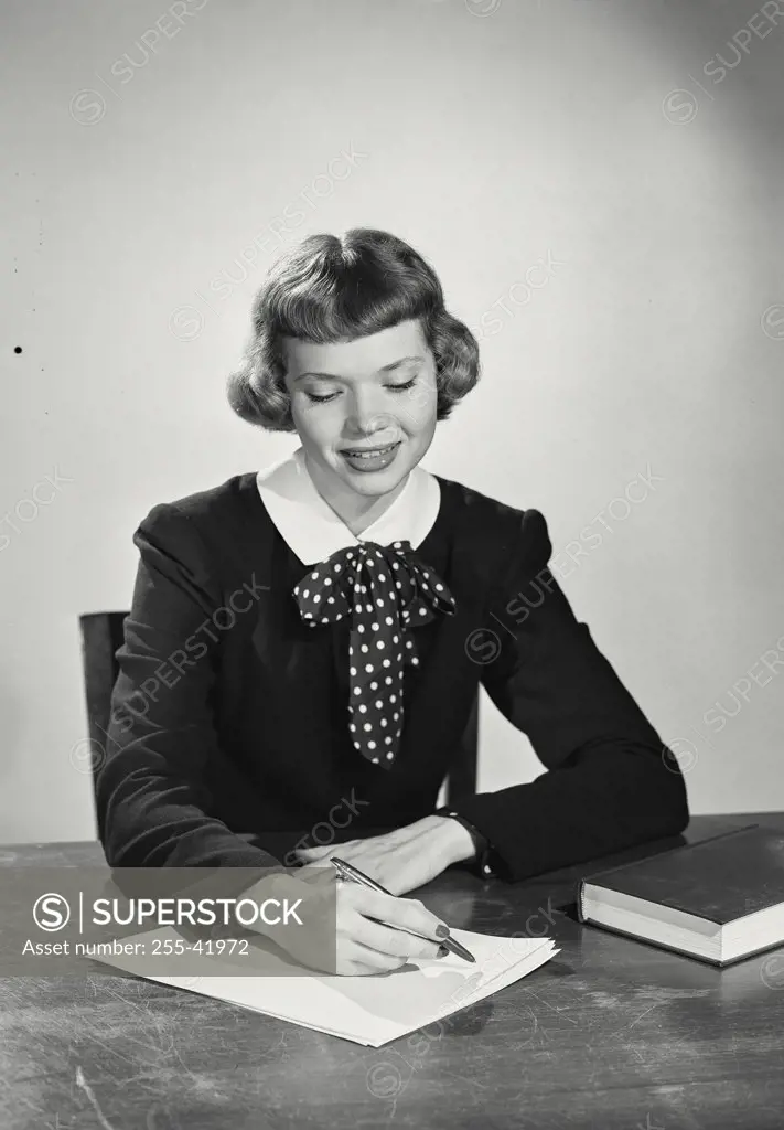 Vintage photograph. Woman with short bangs sitting at desk writing