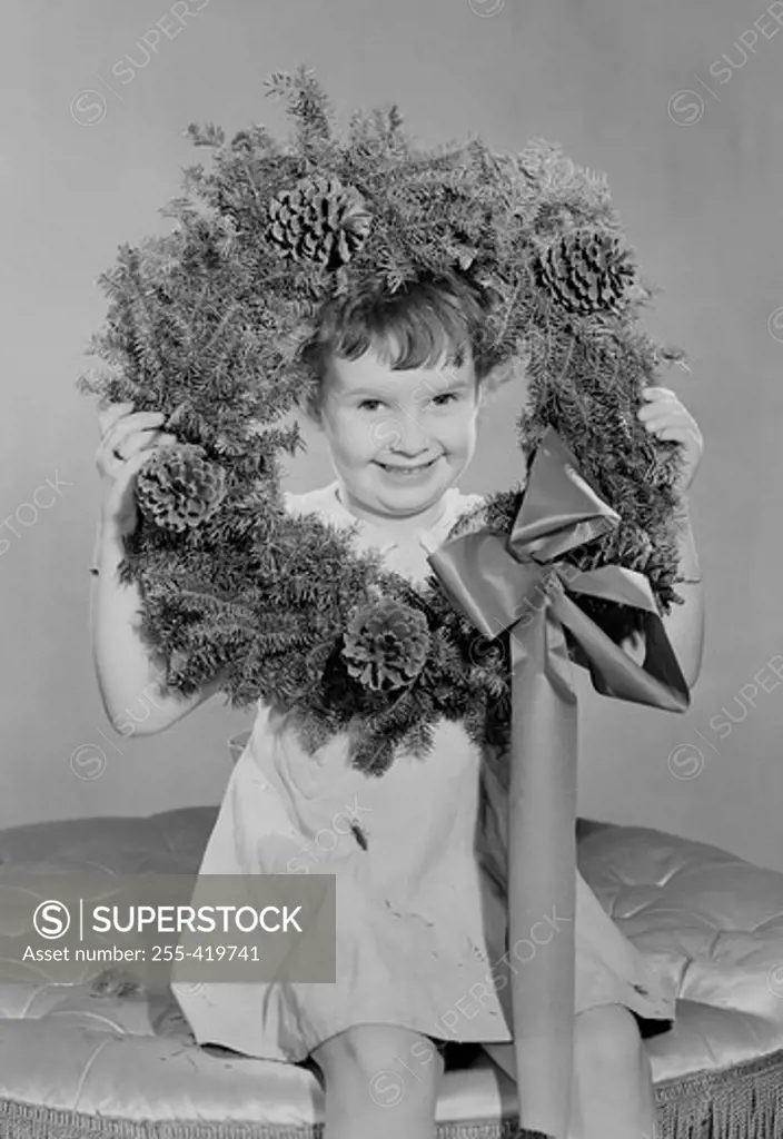Portrait of small girl holding Christmas wreath