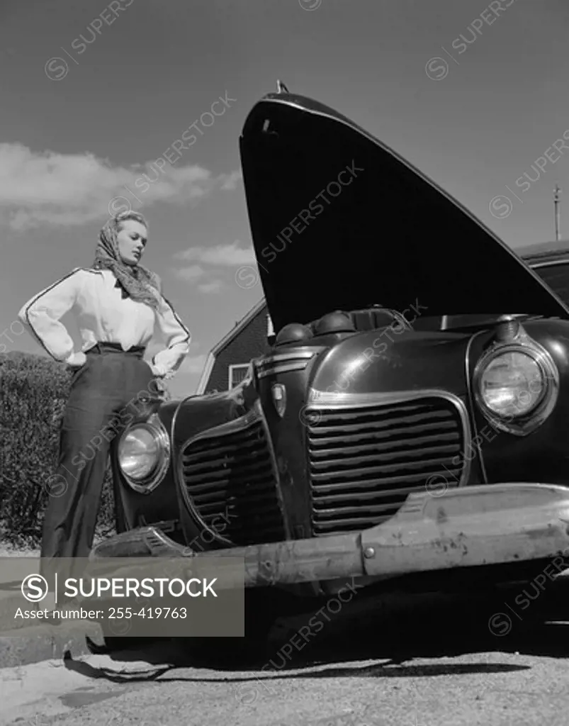 Woman standing by car with open hood