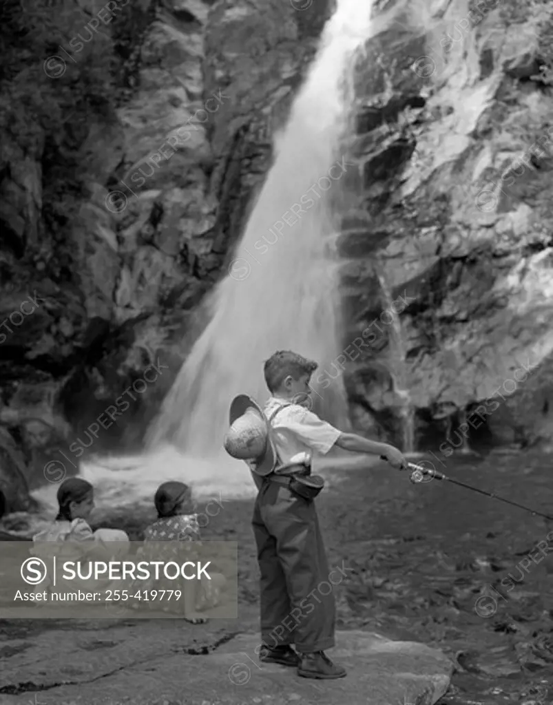 Boy fishing and girls sitting by waterfall