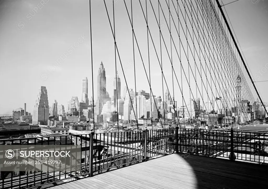 USA, New York State, New York City, Lower Manhattan skyline as seen through cables of the Brooklyn Bridge