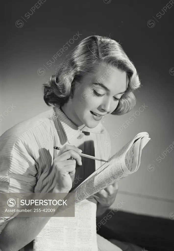 Vintage Photograph. Woman in button shirt reading newspaper