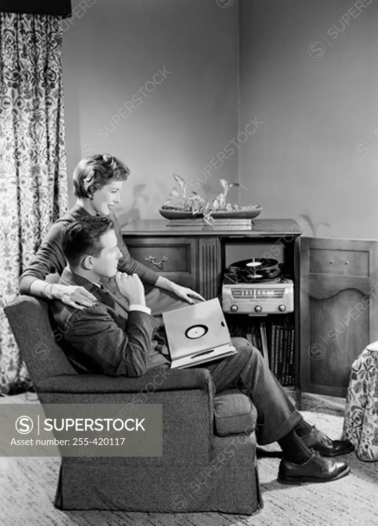 Young couple sitting in living room and listening to music