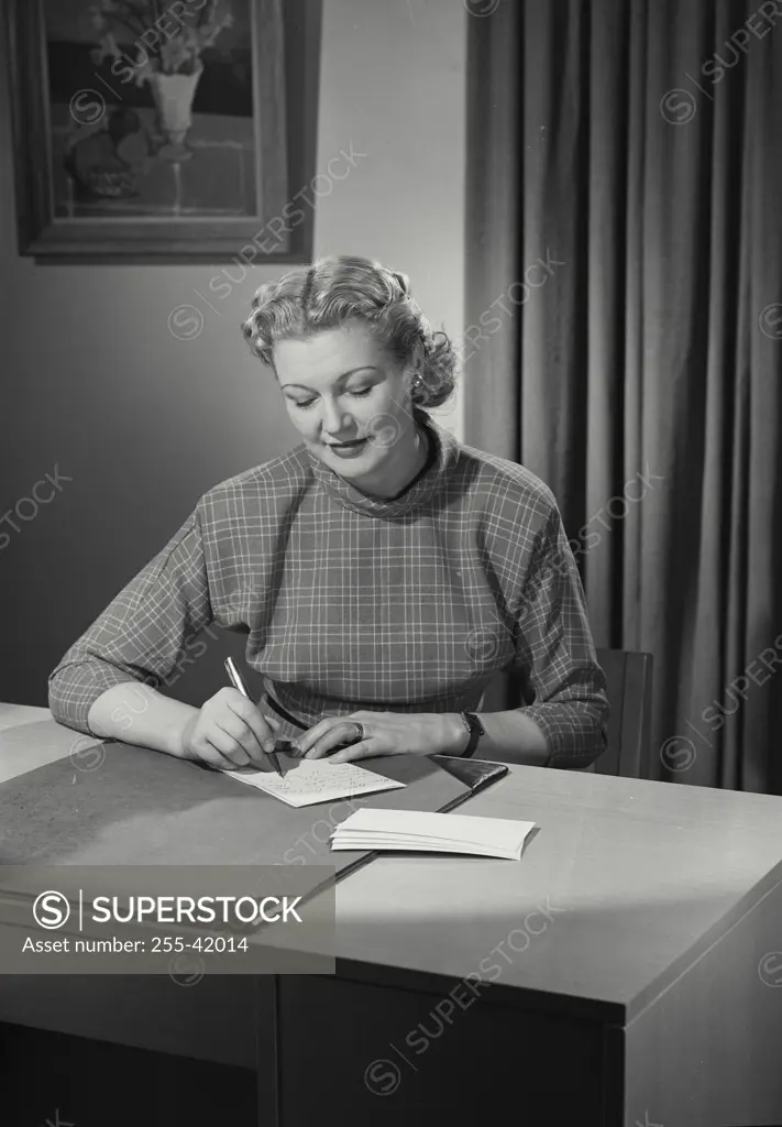 Vintage Photograph. Woman in longsleeve blouse at desk writing a note