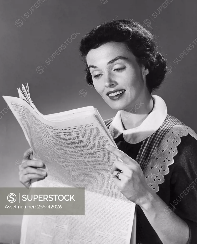 Close-up of a young woman reading a newspaper