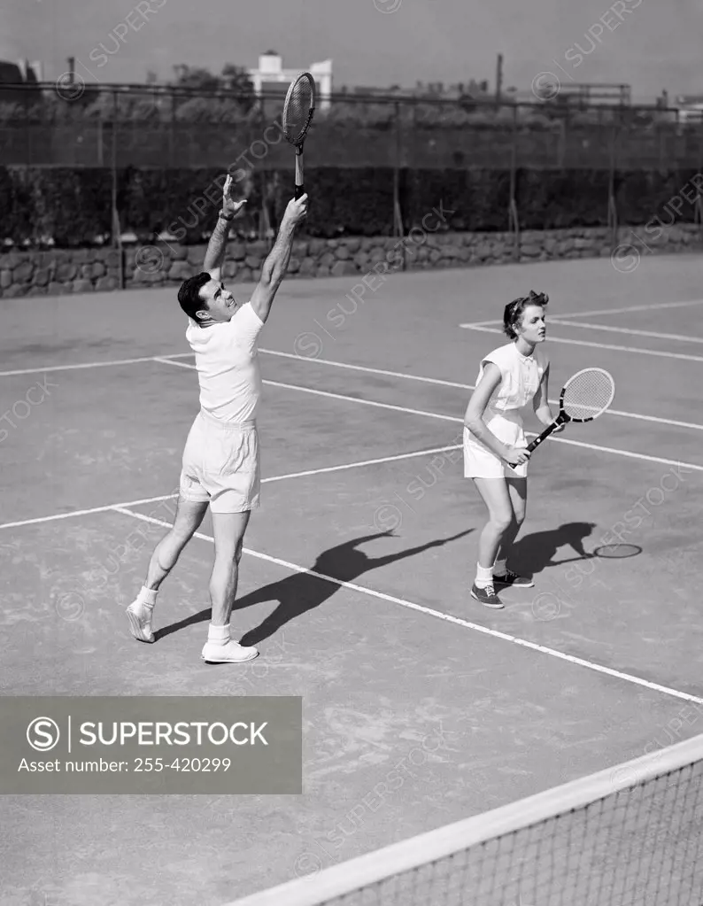 Young couple playing doubles tennis