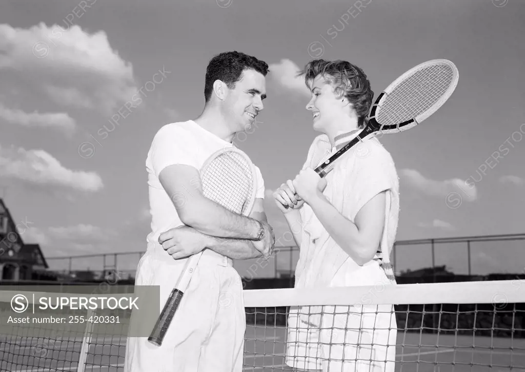 Young couple talking over tennis net