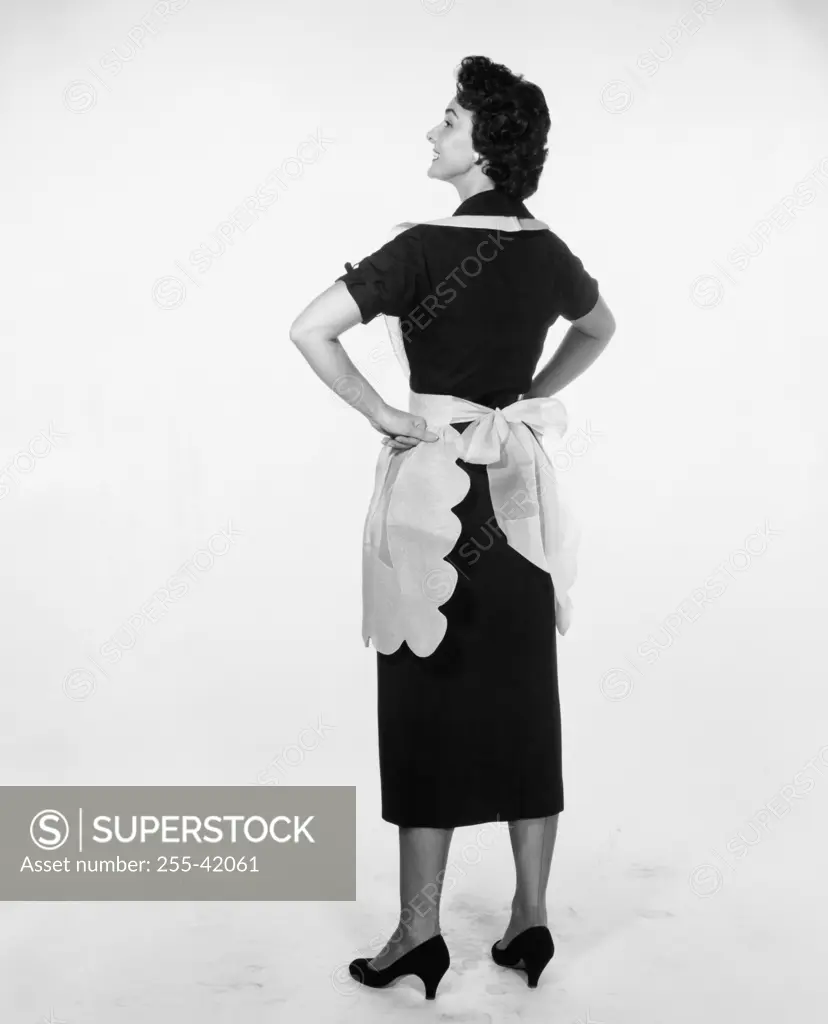 Studio shot of young woman standing with arms akimbo