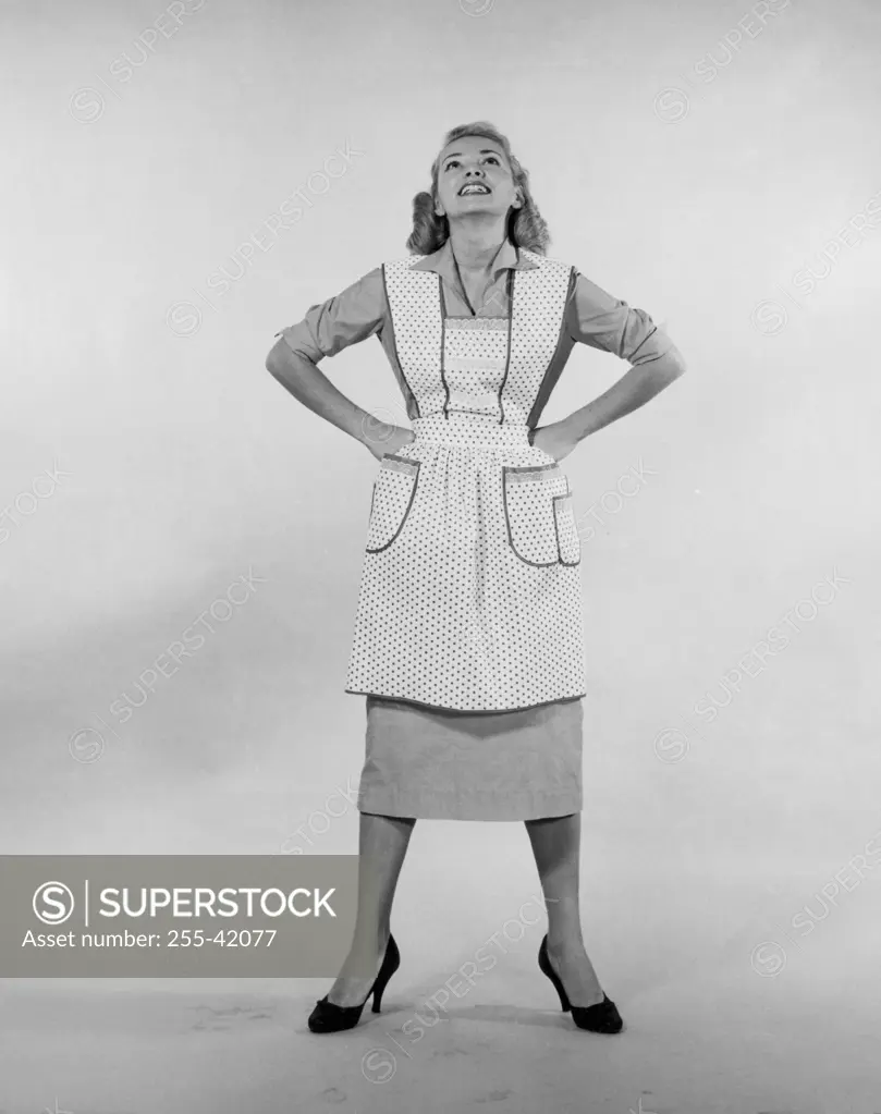Studio shot of young woman standing with arms akimbo