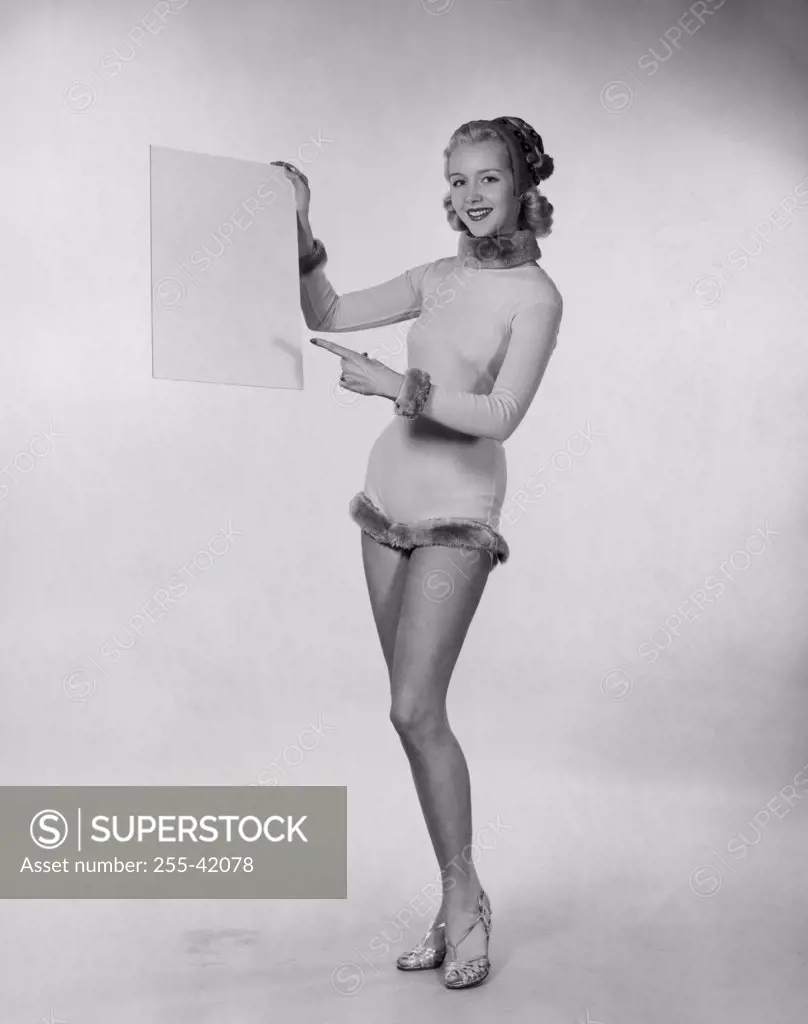 Studio shot of young woman pointing to blank placard