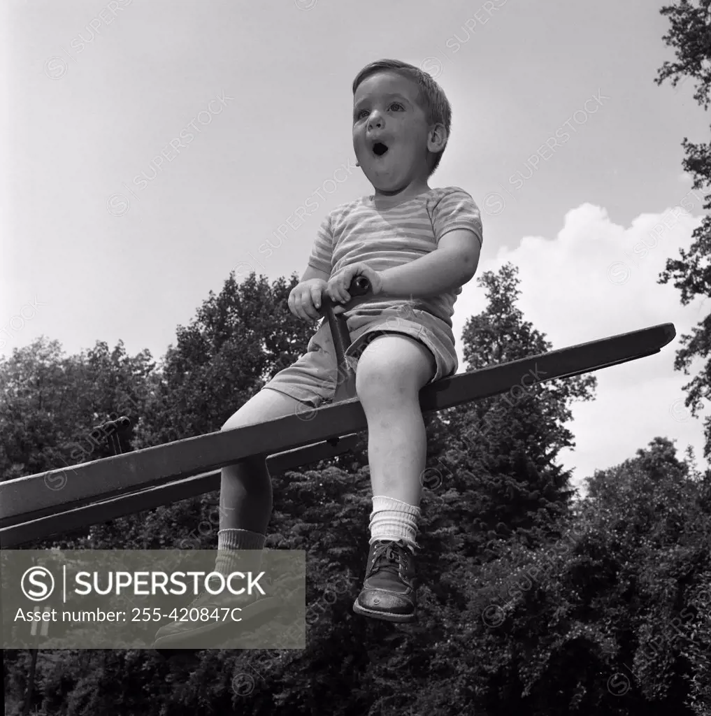Boy sitting on seesaw and making funny face