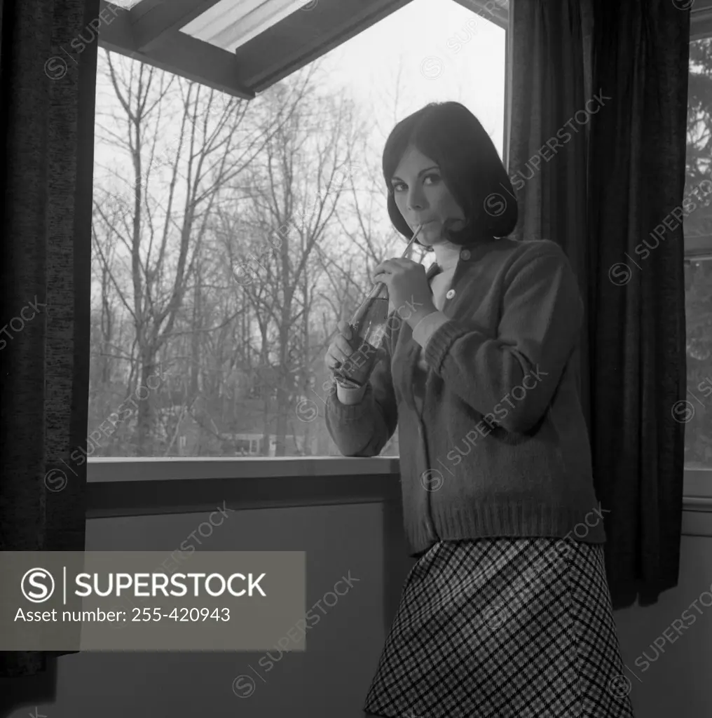 Woman drinking juice by straw straight from bottle