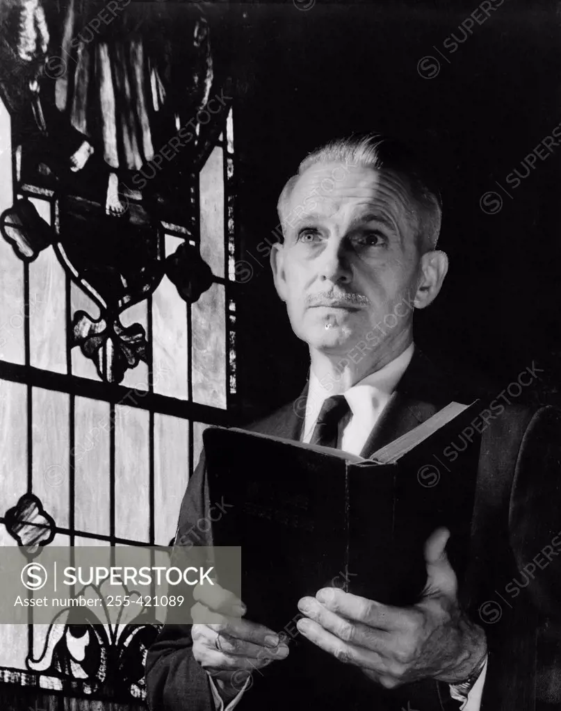 Senior man with book against stained glass window