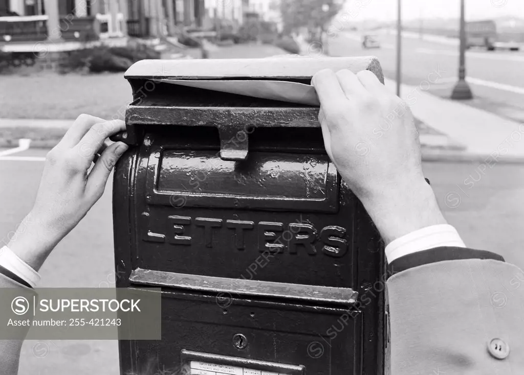 Hands mailing letter in letter box