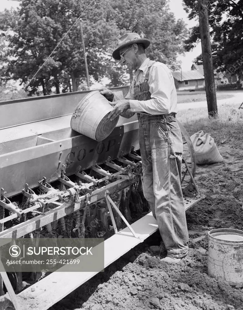 Mature man loading grinds into sowing machine
