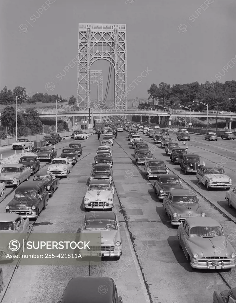 Cars on urban motorway with suspension bridge in background