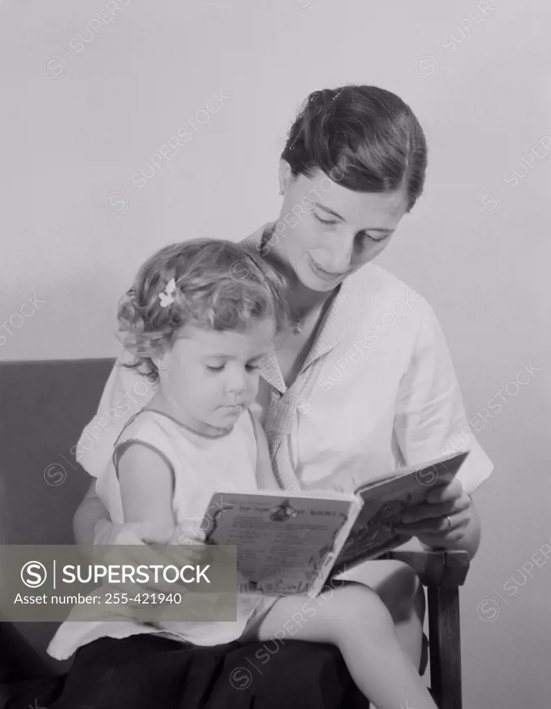 Mother reading book to daughter