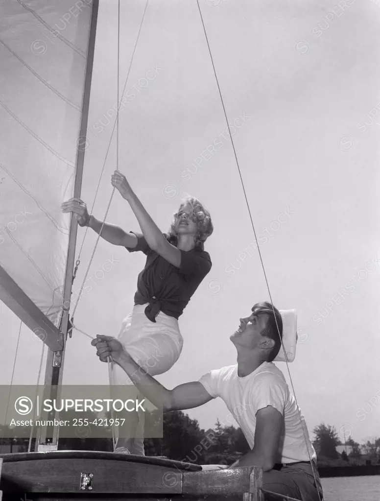 Couple on yacht deck adjusting sail