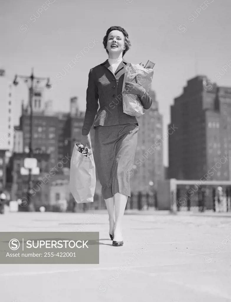 Cheerful businesswoman carrying shopping bags