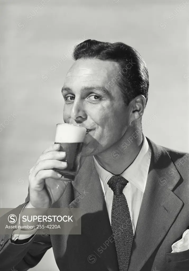 Vintage Photograph. Portrait of man in suit drinking beer from glass