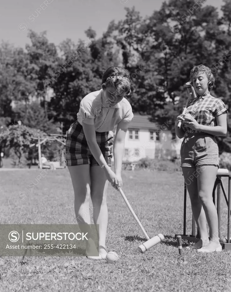 Teenage girls playing croquet