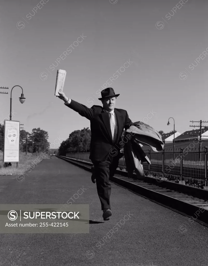 Man with suitcases running along railroad track
