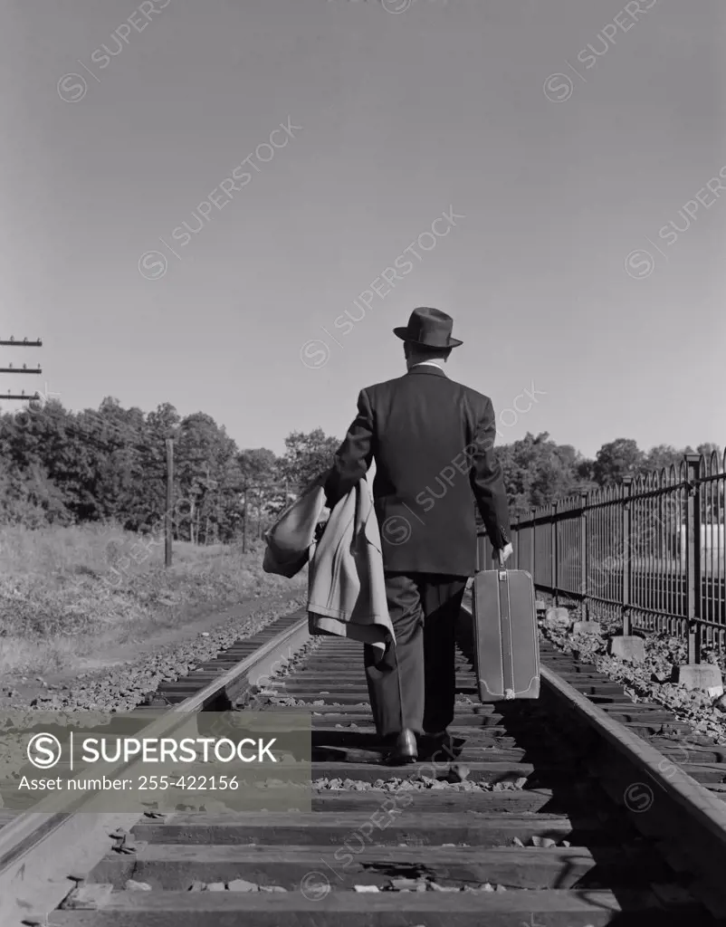 Businessman walking down railway tracks