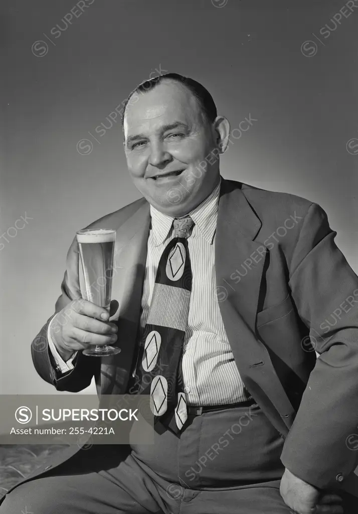 Vintage Photograph. Man in suit smiling with glass of beer