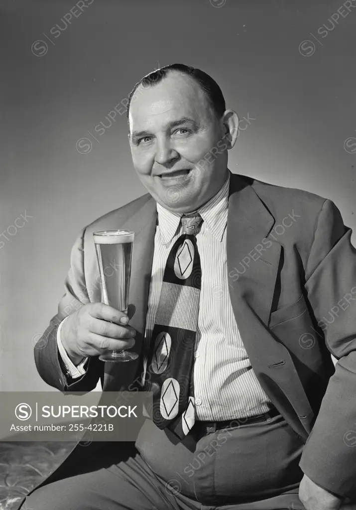 Vintage Photograph. Man in suit smiling with a glass of beer