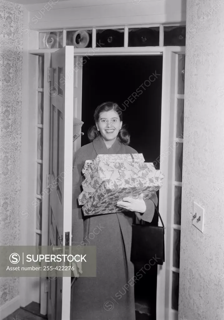 Woman carrying Christmas presents in doorway