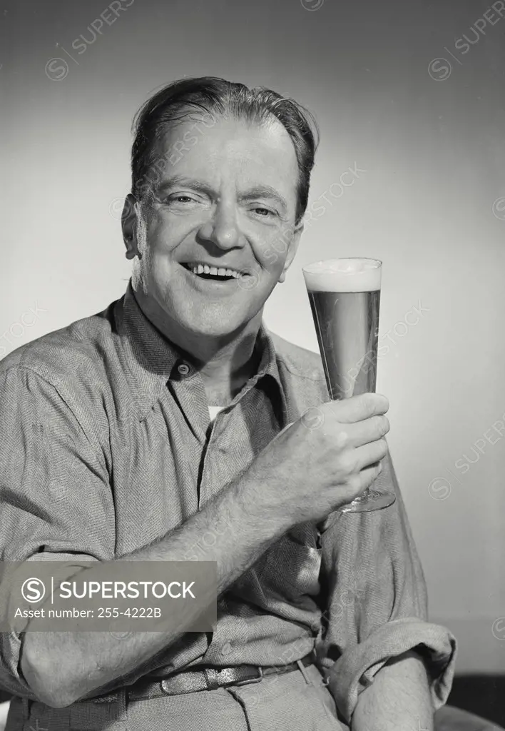 Portrait of man in button shirt holding up glass smiling.