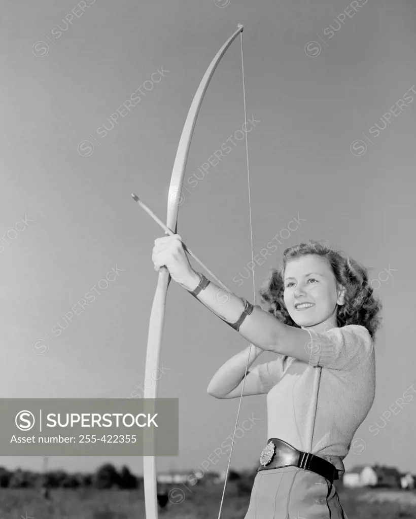 Young woman shooting with bow