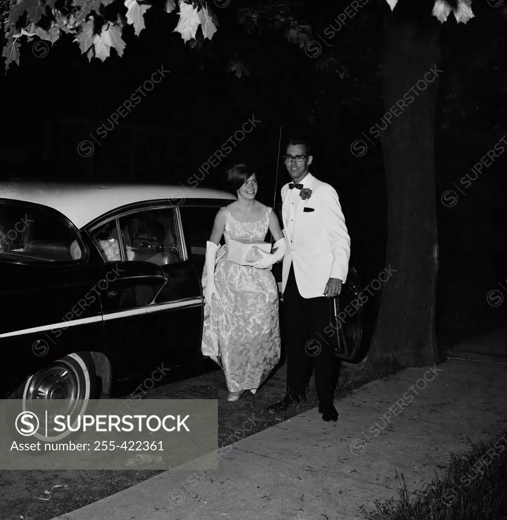 Teenage couple in formal clothes next to car