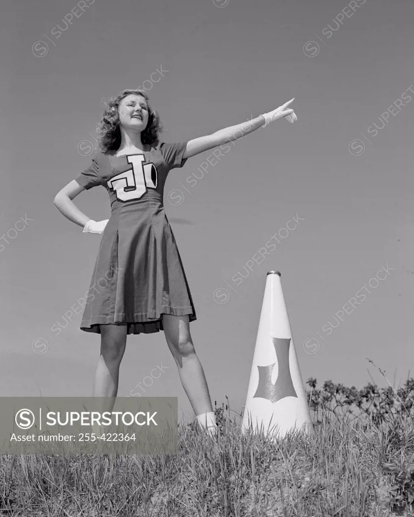 Cheerleader with megaphone in meadow