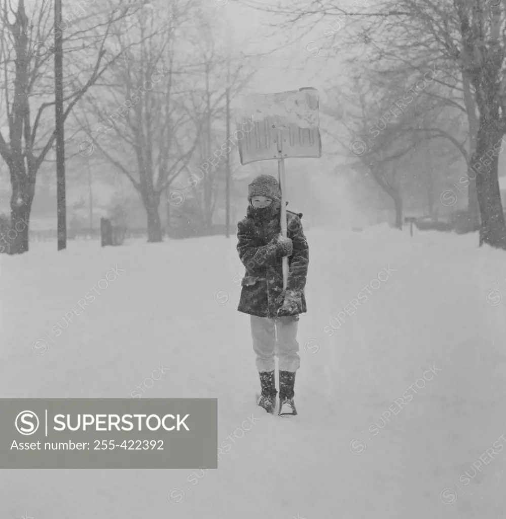 Boy with snow shovel in blizzard