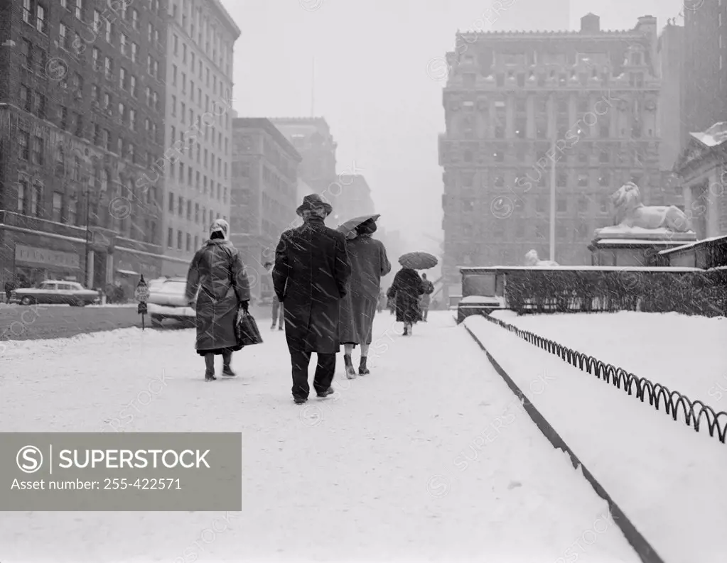 USA, New York City, people walking in snow on Fifth Avenue in front of New York Public Library