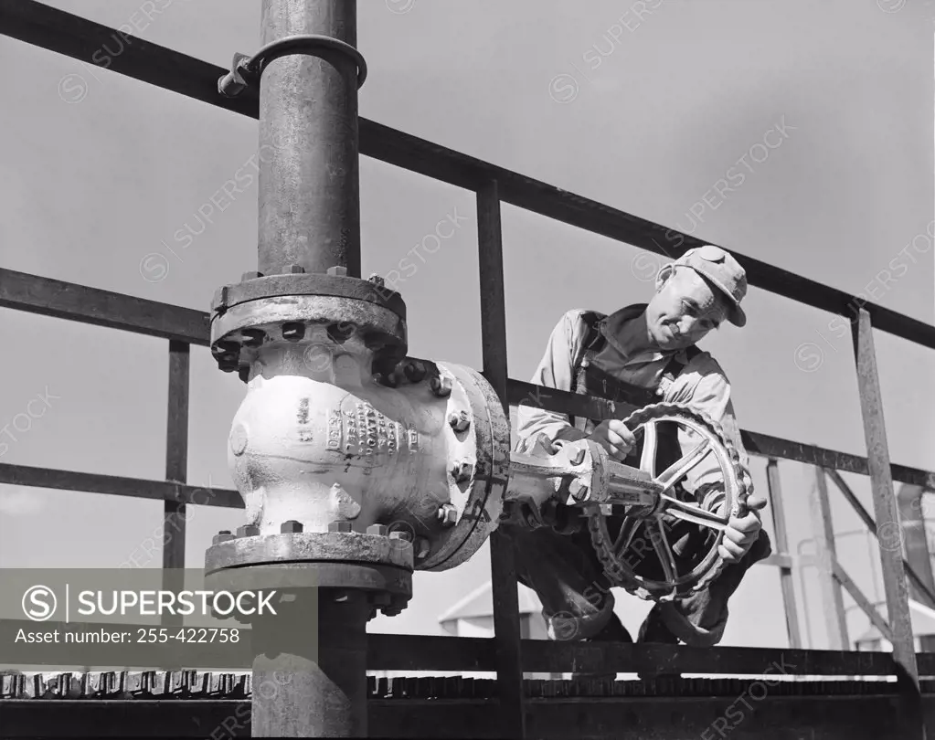 Worker adjusting valve on pipeline
