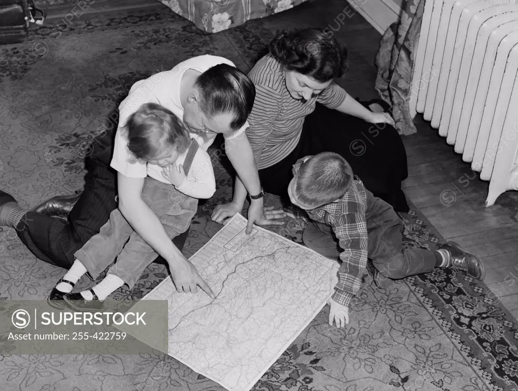 Parents with kids sitting on floor looking at map